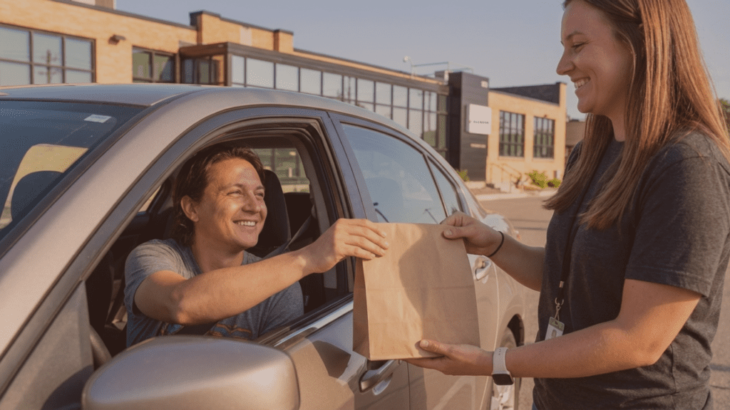 Customer receiving cannabis order through car window from Fluresh Cannabis Adviser at curbside pickup in Grand Rapids