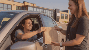 Customer receiving cannabis order through car window from Fluresh Cannabis Adviser at curbside pickup in Grand Rapids